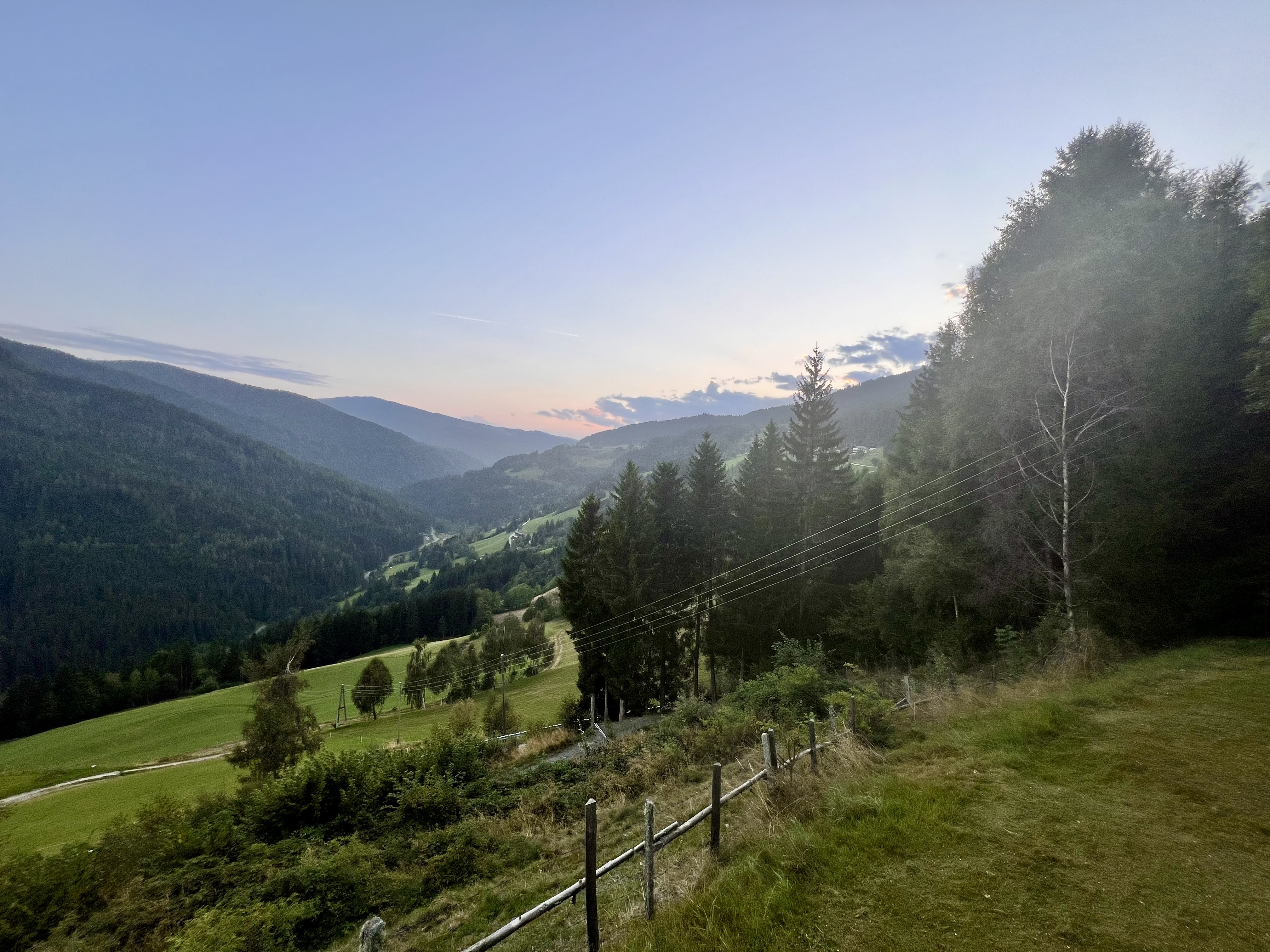 Weiter Blick ins Tal von Außerteuchen in der Abenddämmerung — sanft wellige Berge, Wiesen, Wald
