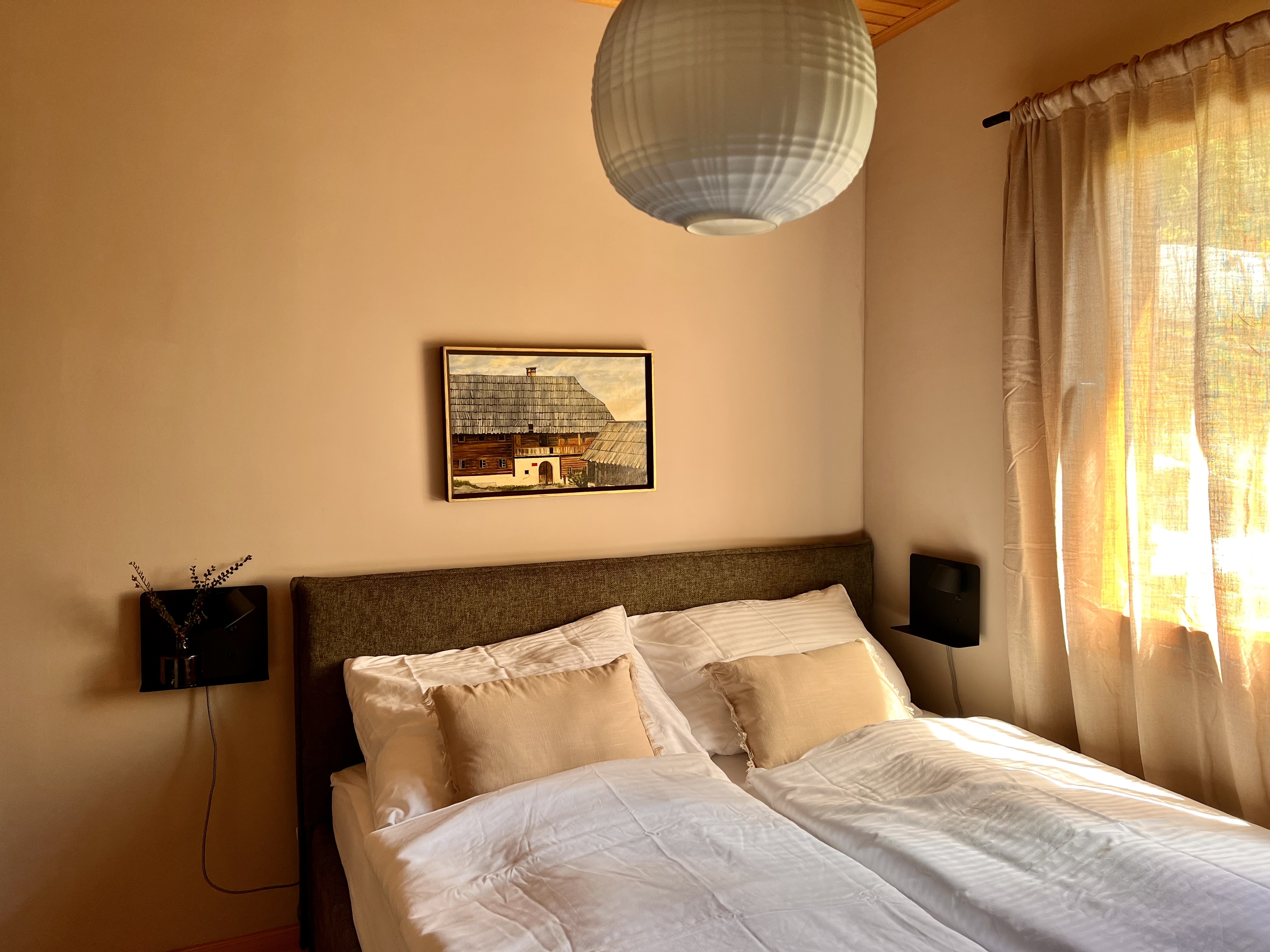 Doppelbett mit Leinenbezug, Bauernbild und Reispapierlampe im Hauptschlafzimmer der alm44