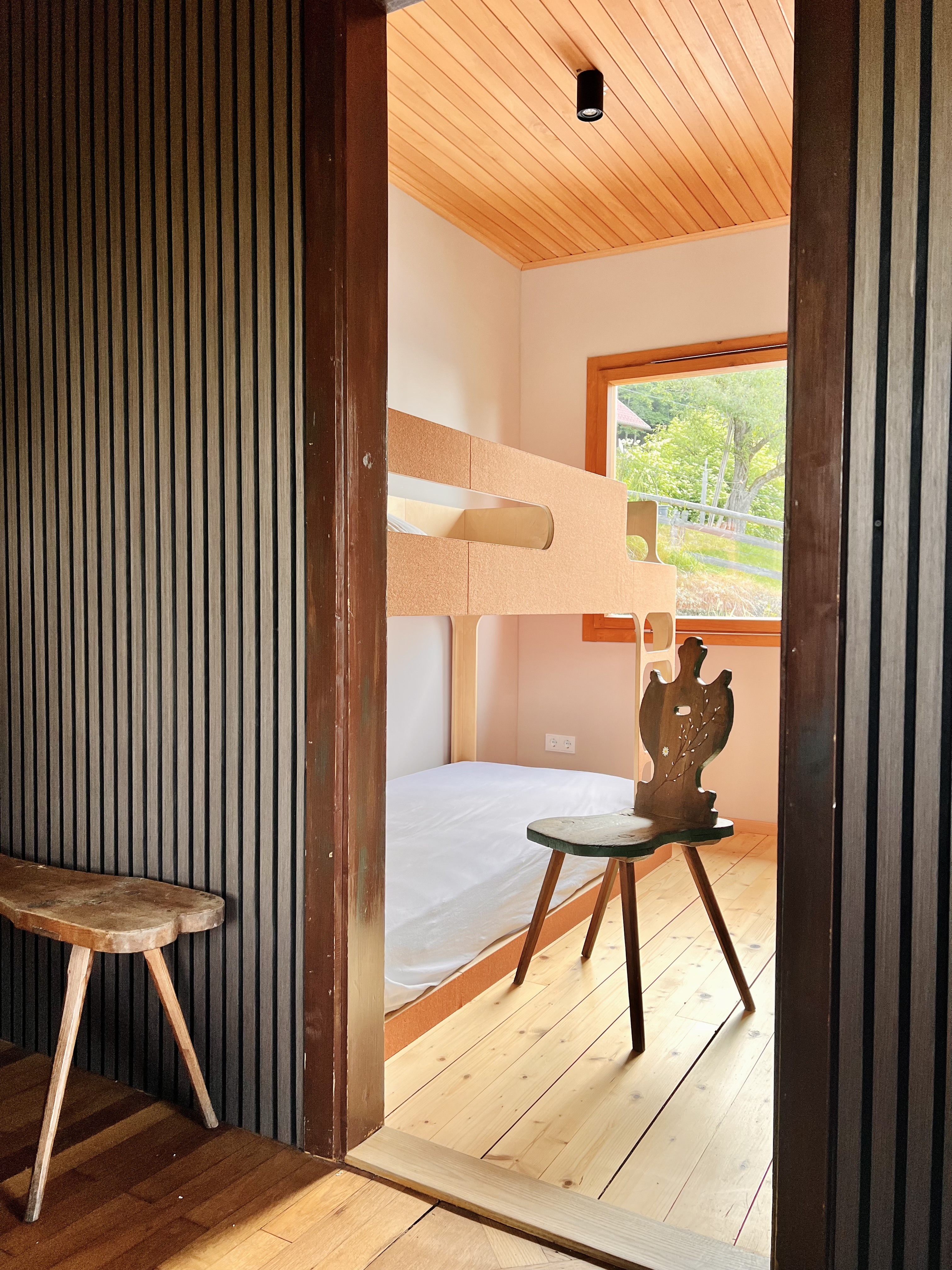 Stockbett mit hellem Holzgestell und alter Bauernstuhl im Kinderzimmer der alm44